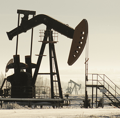 A field with oil pump jacks surrounded by greenery under sunlight
